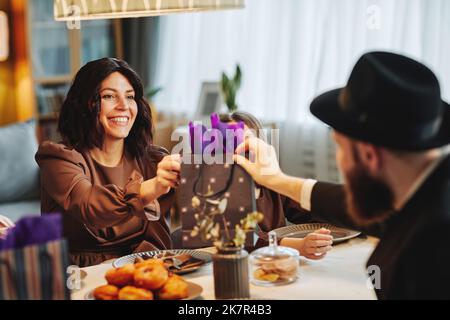 Portrait of adult jewish couple sharing gifts at dinner table in cozy home setting Stock Photo