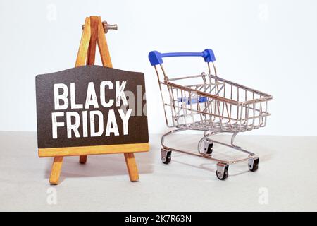 black paper bags in shopping cart on red background, copy space. black friday concept. Stock Photo