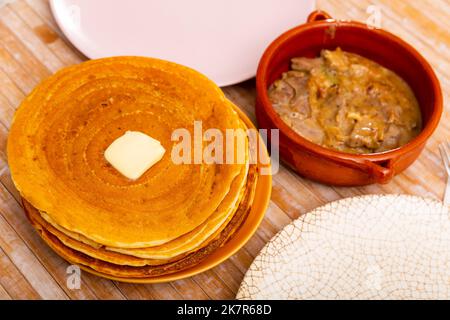 Thin pancakes with butter and machanka of meat with vegetables and mushrooms Stock Photo