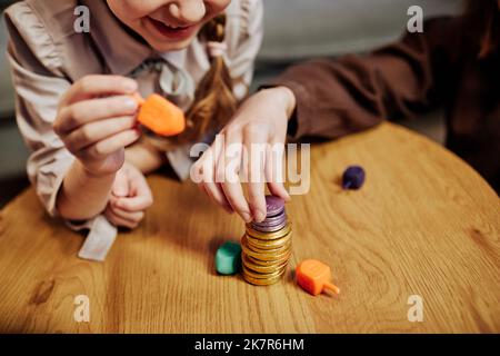 Close up of children stacking chocolate coins while playing jewish dreidel game, copy space Stock Photo