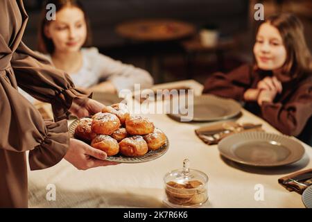 Close up of woman bringing fresh homemade pastry to table in cozy home setting, copy space Stock Photo