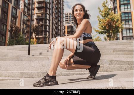 Pretty dark-haired girl in sportswear feeling good after workout Stock Photo