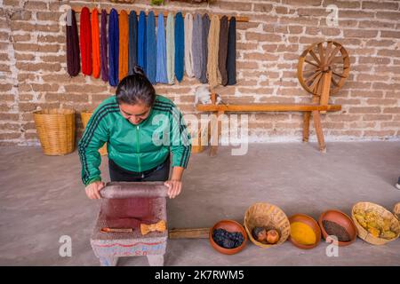 A weaver is grinding minerals for the dyeing of the wool at her home in Teotitlan del Valle, a small town in the Valles Centrales Region near Oaxaca, Stock Photo