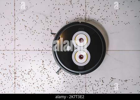 Robotic vacuum cleaner on laminate white tiled floor smart cleaning technology. garbage on the white tiled. top view Stock Photo