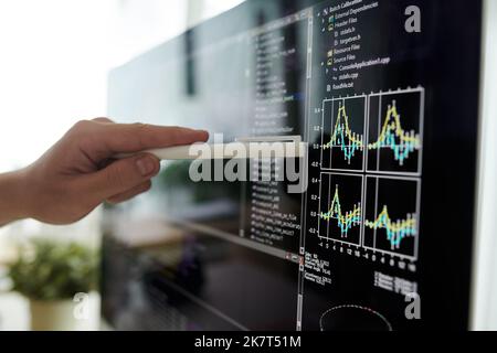 Closeup image of developer pointing at chart on computer screen Stock Photo