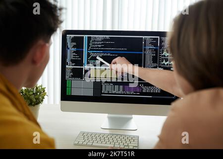 Young developers checking programing code on computer screen Stock Photo