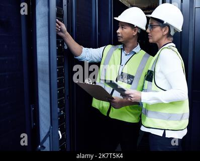 The team to call for your connectivity concerns. two technicians working together in a server room. Stock Photo
