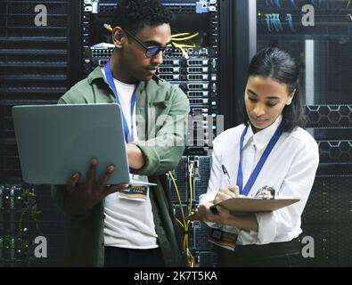 Make a note of this. two technicians working together in a server room. Stock Photo