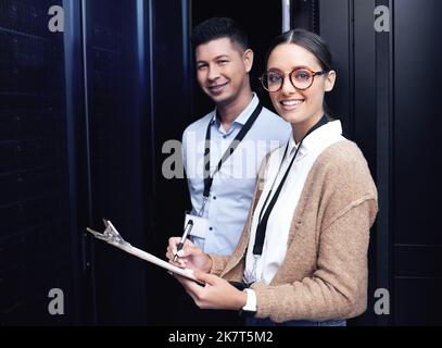 Your system is officially safe. two technicians working together in a server room. Stock Photo