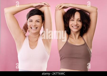 Dont forget to stretch. Cropped portrait of two attractive young female athletes warming up in studio against a grey background. Stock Photo