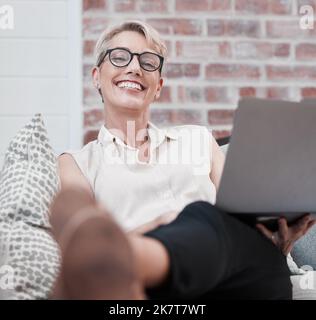 Dont care til Monday. Portrait on an older woman using a laptop and looking relaxed on the sofa at home. Stock Photo