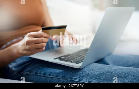 Ive been dying to get this for myself. an unrecognizable woman sitting alone in her living room and using her laptop for online shopping. Stock Photo