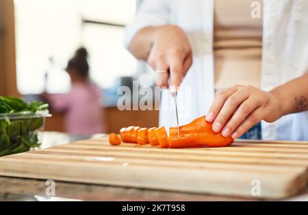 Just add some carrots. a woman chopping carrots at home. Stock Photo