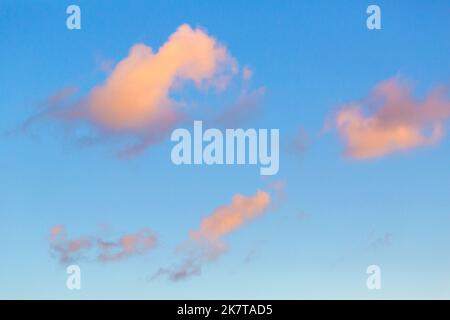Lonely clouds on the blue sky with a strip of clouds at sunset Stock Photo