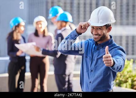 Lets get to work, shall we. a young businessman standing in the city and showing a thumbs up gesture while wearing a hardhat. Stock Photo