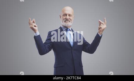 Smiling confident businessman snapping his fingers, isolated on gray background Stock Photo