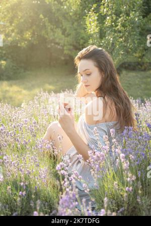 Beautiful girl is drinking  wine in lavender field Stock Photo
