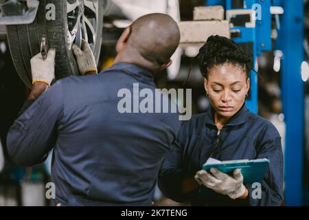Mechanic team worker Black African working together to service fix check car tire together in garage Stock Photo