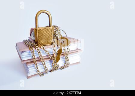 Miniature paper journals secured with chain and keyed padlock. Outsource bookkeeping security practices. Stock Photo