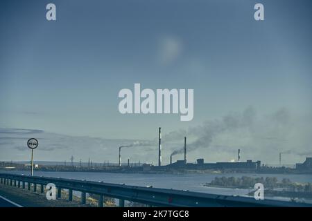 Industrial landscape with heavy pollution produced by a large factory. Pipes on the territory of the plant. Stock Photo