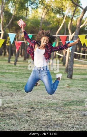 Happy and excited woman jumping and smiling while celebrating her birthday outdoors in the nature. Stock Photo