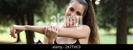 Young woman stretching arms before morning workout on fresh air Stock Photo