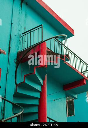 Beautiful spiral staircase on the side of a green and red color building in Perlis, Malaysia. Stock Photo