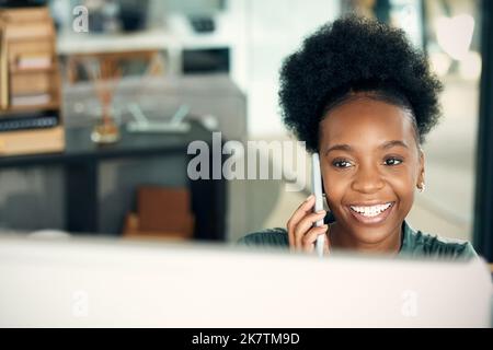 Working hard till she receives the results she wants. a young businesswoman talking on a cellphone while working on a computer in an office. Stock Photo