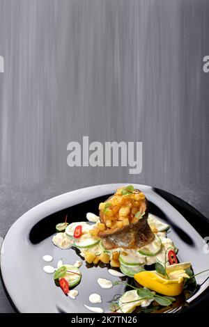 Grilled trout fillet with vegetables, on black background. Vertical Stock Photo