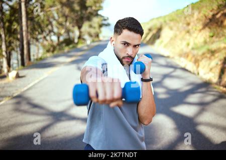 Perfecting his speed, agility and strength. Portrait of a sporty young man doing dumbbell punches while exercising outdoors. Stock Photo