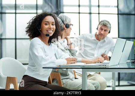 female call center worker accompanied by her team working in the office. Stock Photo