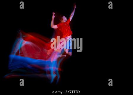 Professional volleyball player hitting ball in jump isolated on dark background with mixed light effect. Art, sport, team, competition, championship Stock Photo