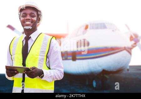 African technician engineer fixing the engine of the airplane with using tablet Stock Photo