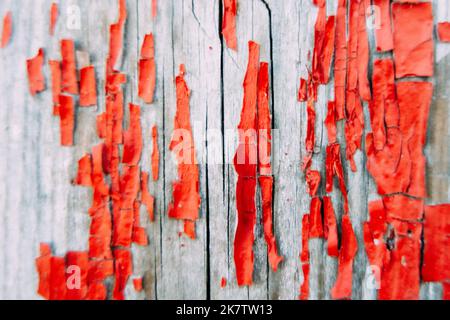 Natural texture for background and design. Old cracked flaking bright red paint on wooden wall or door. Weathered rough painted surface with patterns Stock Photo