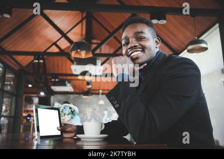 African business man using tablet and having a happy time with good idea thinking in coffee shop Stock Photo