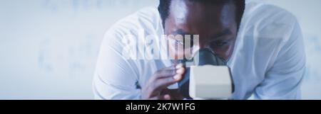 Close Up of a African Male Scientist Looking into the Microscope. Concept of Microbiologist Working on Molecule Samples in Modern Laboratory with Tech Stock Photo