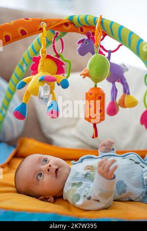 Baby playing on colorful play gym Stock Photo