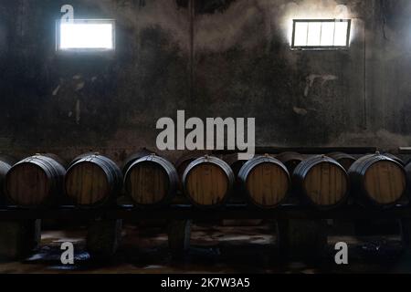 Wine aging in wooden barrels on a dark wine cellar Stock Photo