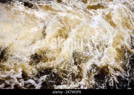 Wake brown water bubbling behind ship with bubbles and splashes background texture. Stock Photo