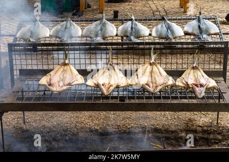 Different types of fish cooked over a fire at a food festival in Estoril, Stock Photo