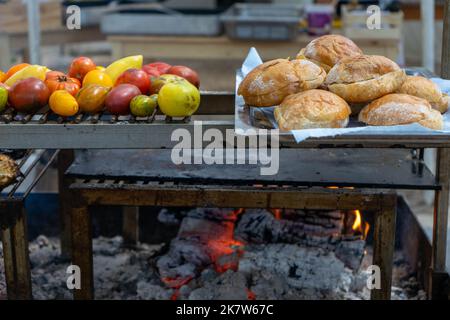 Several different types of tomatoes and bread cooking over a fire at a food festival in Estoril, Portugal Stock Photo