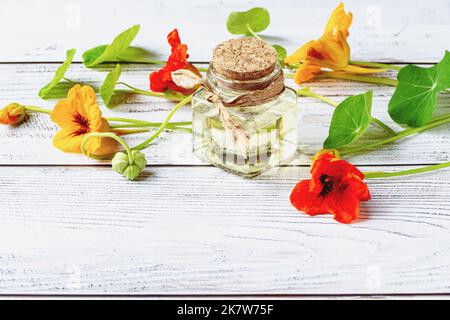 Nasturtium Herb Oil of flowers leaves seeds, nasturtium extract in bottle on wooden background Stock Photo