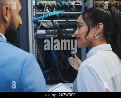 Do we understand each other. two workers inspecting the electronic equipment in a server room together at work. Stock Photo