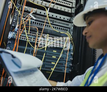 Mama would be proud. a young woman working on cables in a server room. Stock Photo