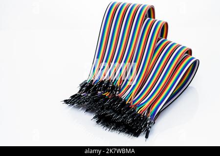 Ribbon cable or multi-wire planar cable on white background. Flat ribbon cable with pin connectors. Multi-colored ribbon computer connecting cable. Stock Photo