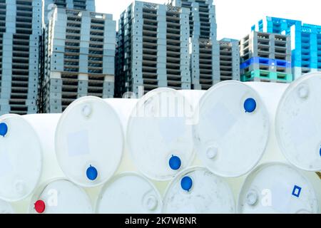 Old chemical barrels. Empty white chemical drums stack on blur industrial plastic pallets. Toxic waste warehouse. Hazard chemical barrel. Industrial Stock Photo