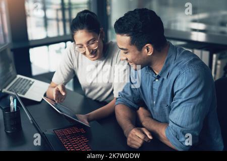 like flowing bananas, peel this back. two young workers using a digital tablet in a modern office. Stock Photo