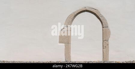 White plastered old wall with a worked into stony archway Stock Photo