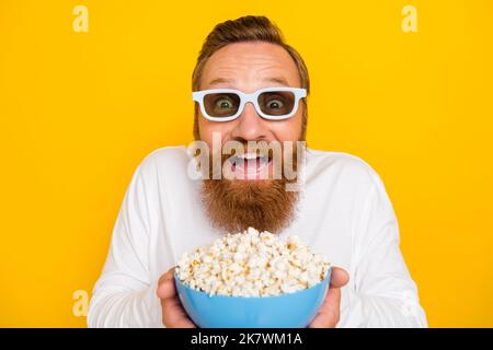 Photo of hooray beard red hair man give popcorn watch movie wear eyewear white shirt isolated on yellow color background Stock Photo