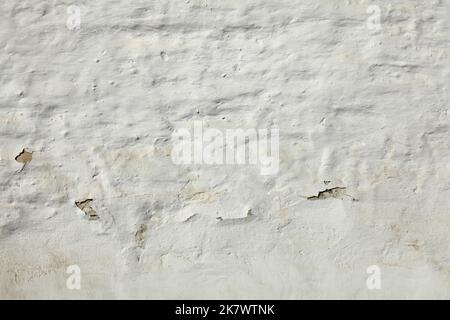 Old and cracked, dilapidated and uneven brick wall, painted with whitening. Texture and background of building wall, painted with whiting. Backdrop Stock Photo